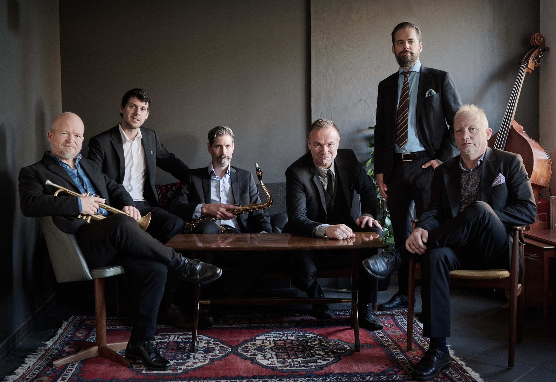 Bandmedlemmarna i Second line jazzband sitter runt ett soffbord.