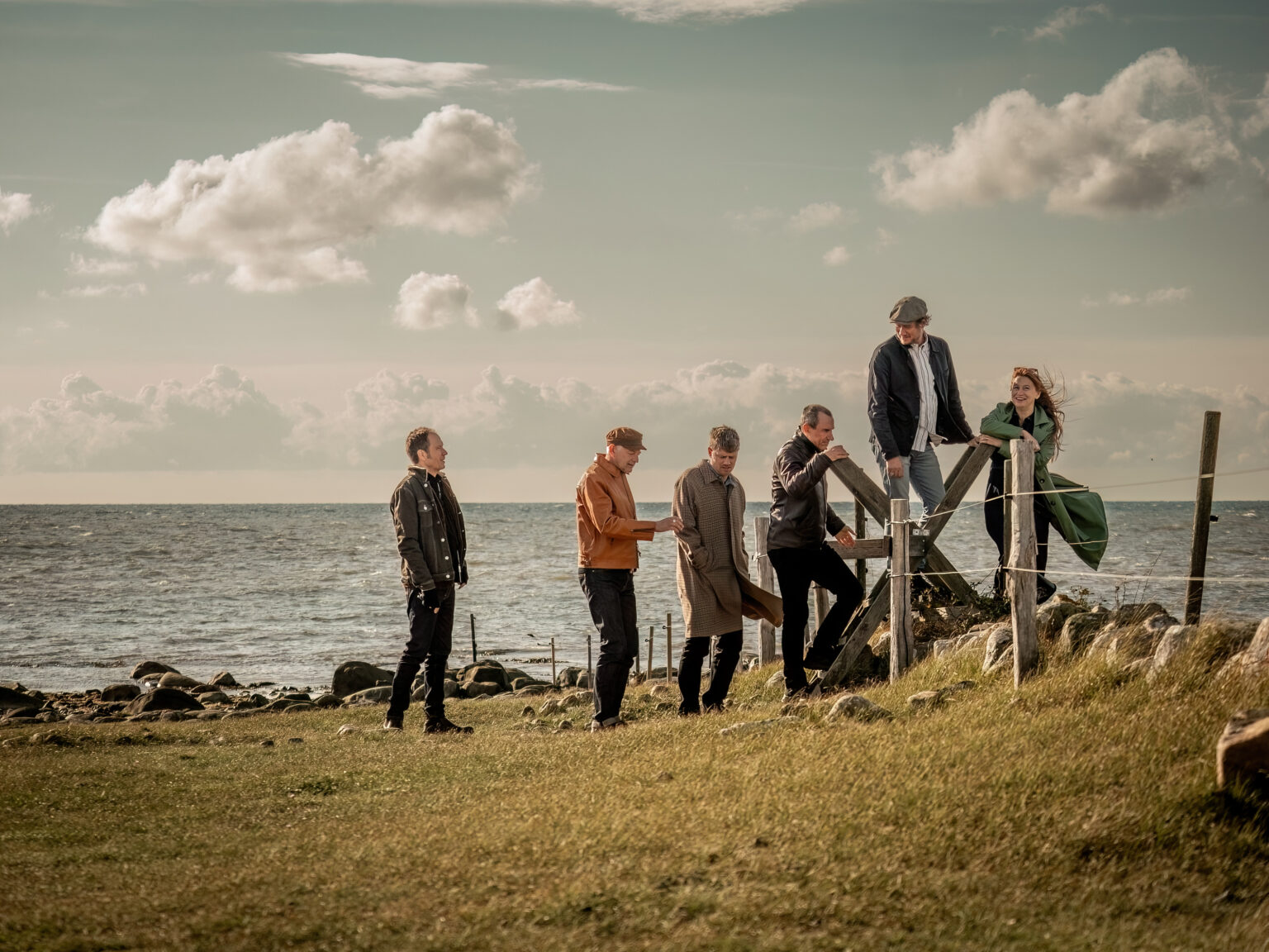 West of Eden 8 Foto Anders Johansson Bandmedlemmarna klättar över ett staket. Havet syns i bakgrunden.